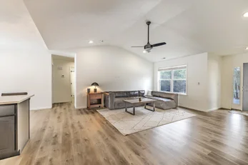 Cozy cabin-style living and dining area with wood beam ceiling, sofa, dining table, and kitchenette - professional short term rental photography